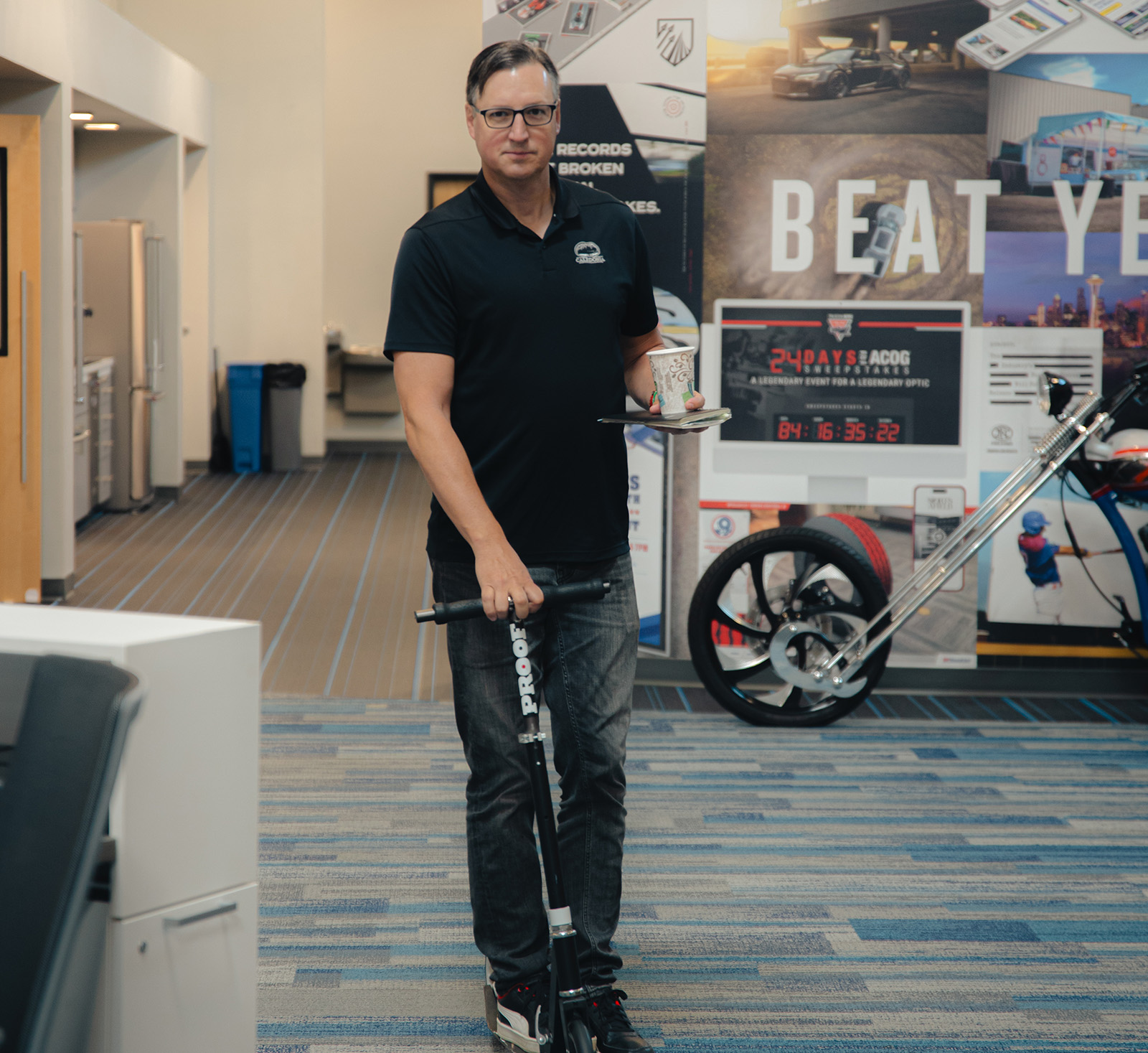 Creative Director riding a scooter holding a notebook and a coffee cup