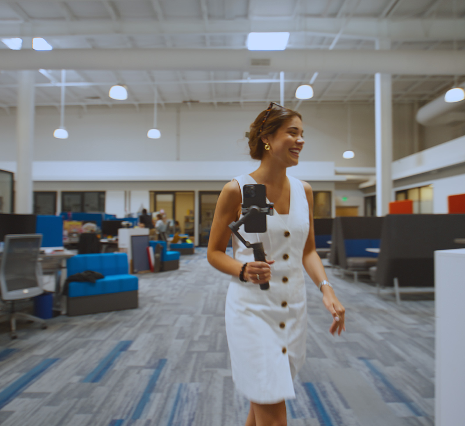 Woman walking through an office carrying an iPhone on a gimble mount